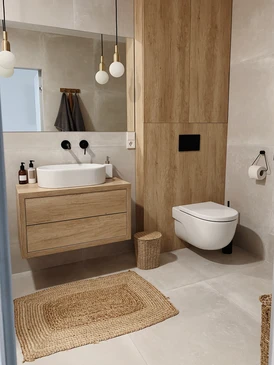 Salle de bain moderne avec mobilier suspendu en bois clair, vasque rectangulaire blanche posée, robinetterie murale noire mat